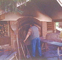 Der B&auml;cker im Hof vor dem mit Holz hei&szlig; gemachten Backofen